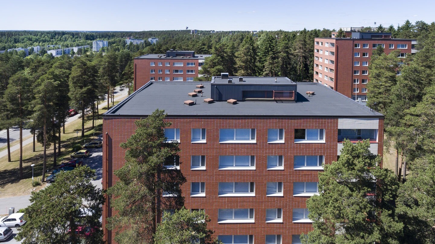 KOY Harmaaleppä Lahti, kolme punatiilistä kerrostaloa joissa mustat bitumikermikatot, ympärillä puita